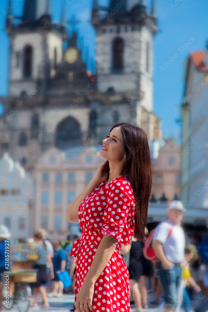 Beautiful brunette girl in red dress travel in Prague, city streets