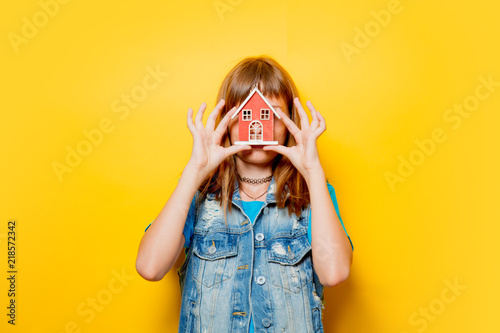 Tablou pe pânză portrait of young teenage girl with toy house on yellow background