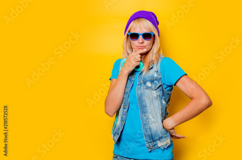 portrait of young trendy girl in hat and headphones on yellow background