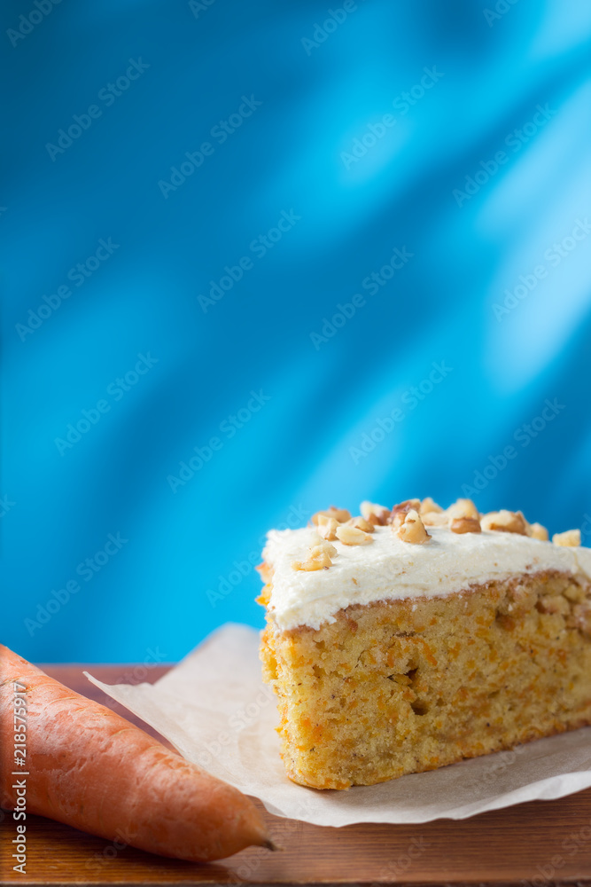 Piece of carrot cake on parchment with copy space on blue background Piece of carrot cake on parchment with copy space on blue background
