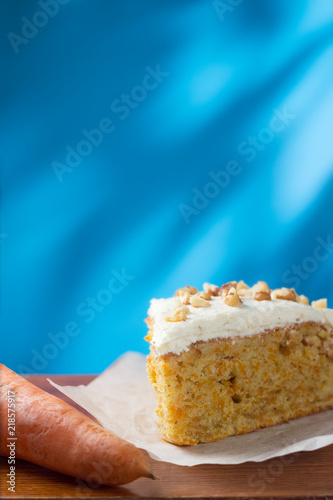 Piece of carrot cake on parchment with copy space on blue background
