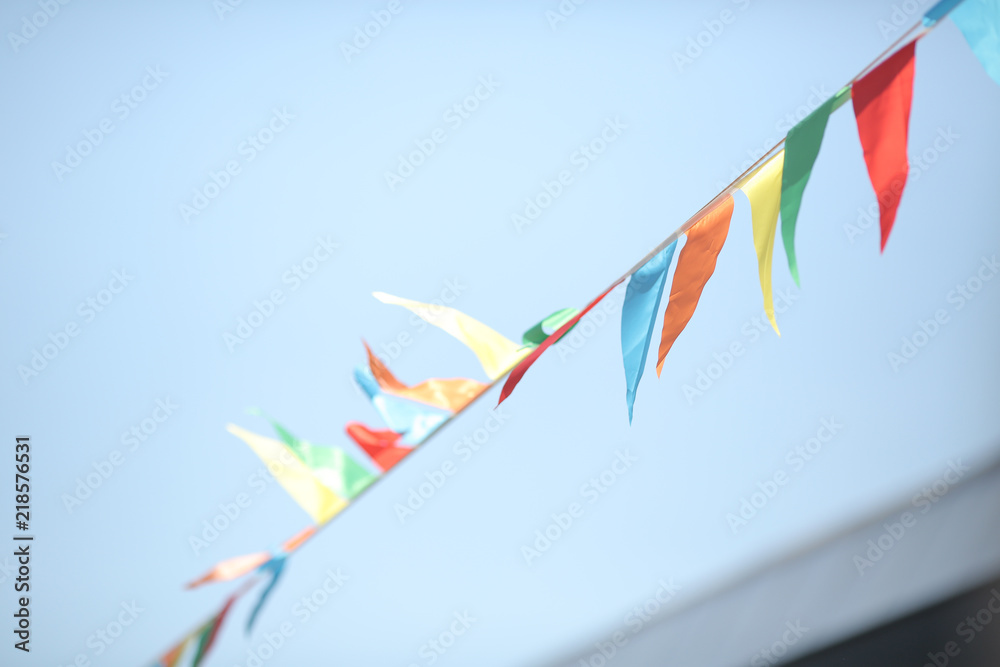 multicolored fabric flags develop from the wind against the blue sky. celebration multicolored fabric flags develop from the wind against the blue sky. celebration