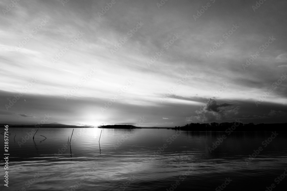 Fototapeta premium A shoot of a sunset over a lake, with sun coming down behind and island