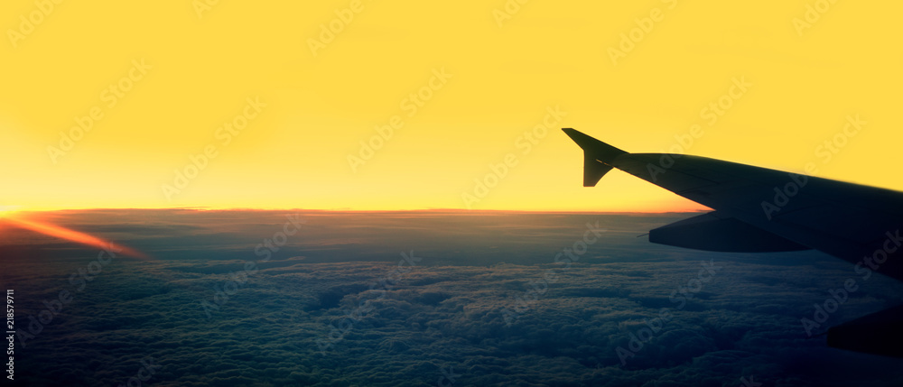 Passenger airplane.  View from airplane window on the wing during  sunset over the clouds. Business trip. Travel concept.