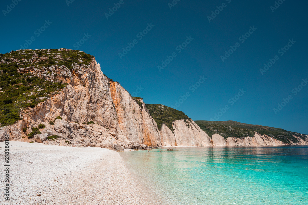 Fteri beach in Kefalonia Island, Greece. One of the most beautiful untouched pebble beach with pure azure emerald sea water surrounded by high white rocky cliffs of Kefalonia