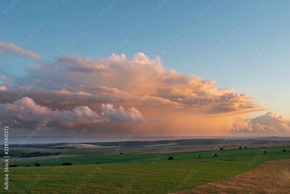 Stunning Summer sunset landscape image of South Downs National Park in English countryisde with orange rain clouds out to sea