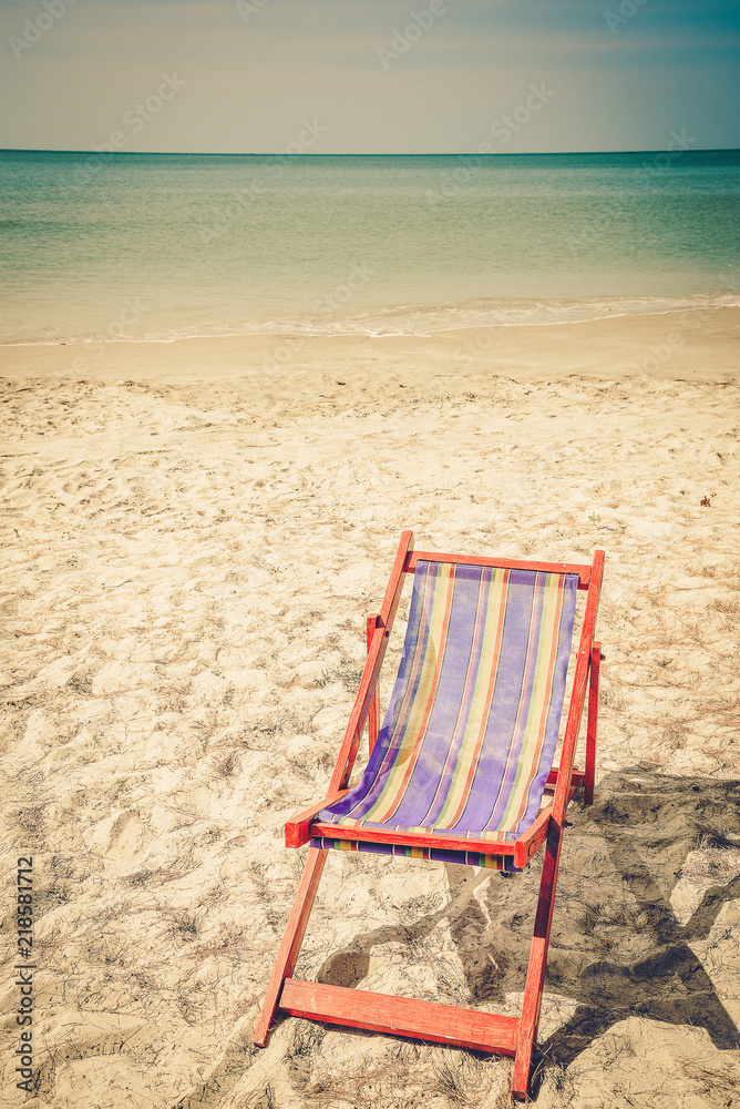 A portrait of a pair of beach chair with umbrella in a seashore A portrait of a pair of beach chair with umbrella in a seashore