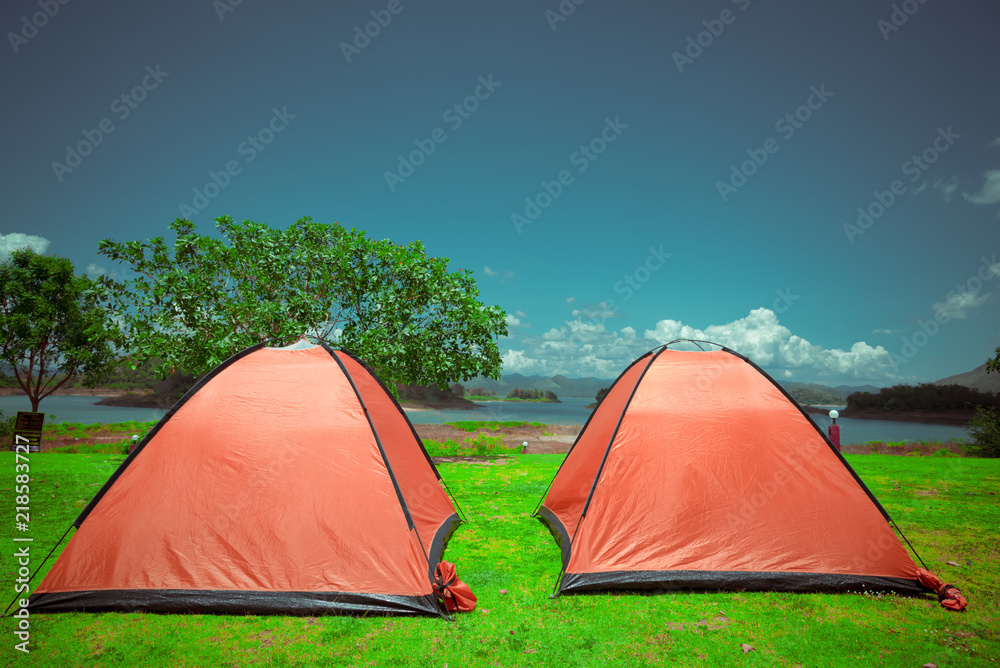Big yellow family sized camping tent in the nice field with mountains on background