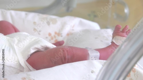 Little feet and hand a newborn baby and newborn babies sleepiing at nursery  at the hospital, focus Neonatology,Cared for by a doctor neonatologist and nurse. Medical devices cardiogram cannula tube. photo