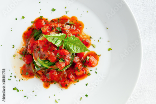 parboiled zucchini with tomato sauce decorated with basil leafs