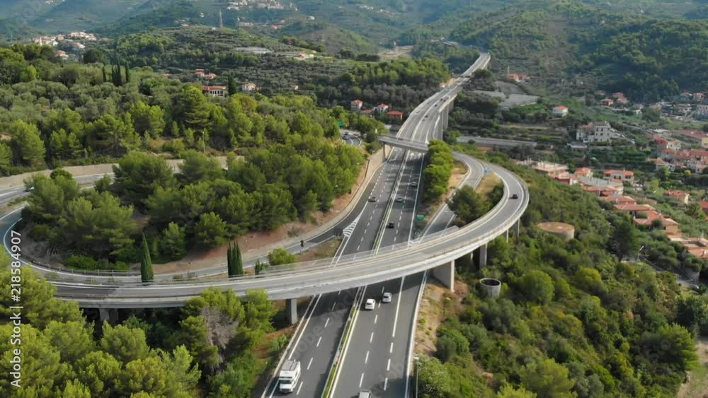 Aerial slow motion: flying near multiple lane highway crossing villages and forest hills (Autostrada dei Fiori - A10) Liguria Italy.