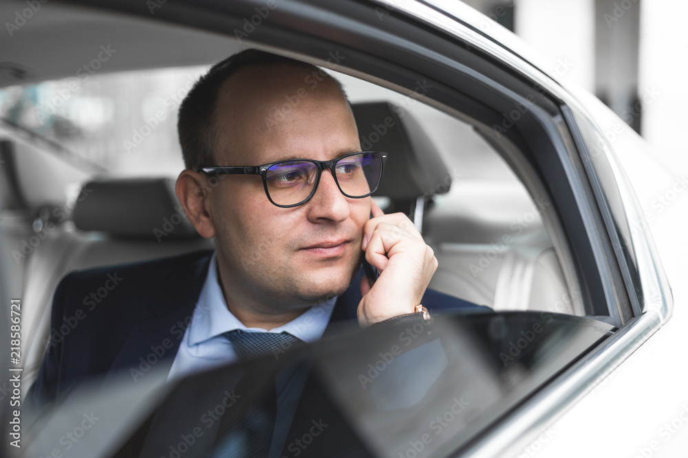 young successful businessman talking on the phone sitting in the back seat of an elite car, talks and business meetings young successful businessman talking on the phone sitting in the back seat of an elite car, talks and business meetings