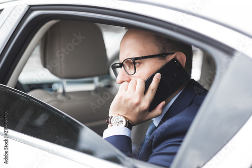 young successful businessman talking on the phone sitting in the back seat of an elite car, talks and business meetings © xartproduction