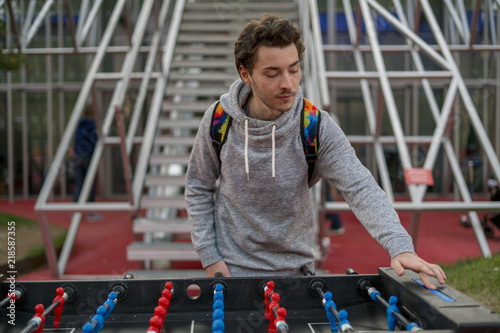 Photography young man playing tablefootball and changing score in park in moscow