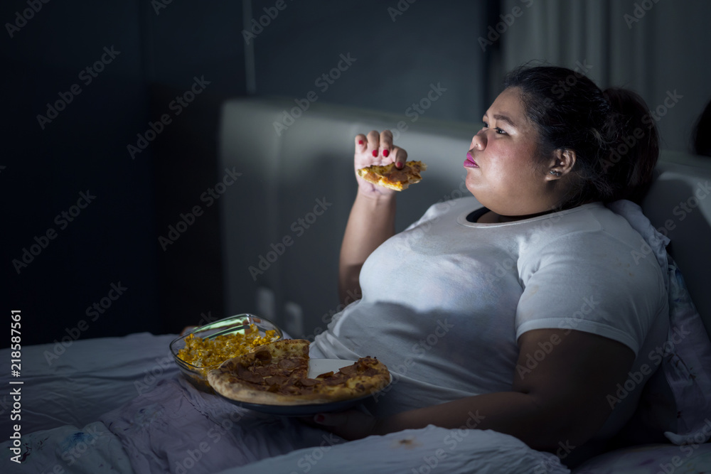 Fat woman eating pizza on bed Stock Photo | Adobe Stock