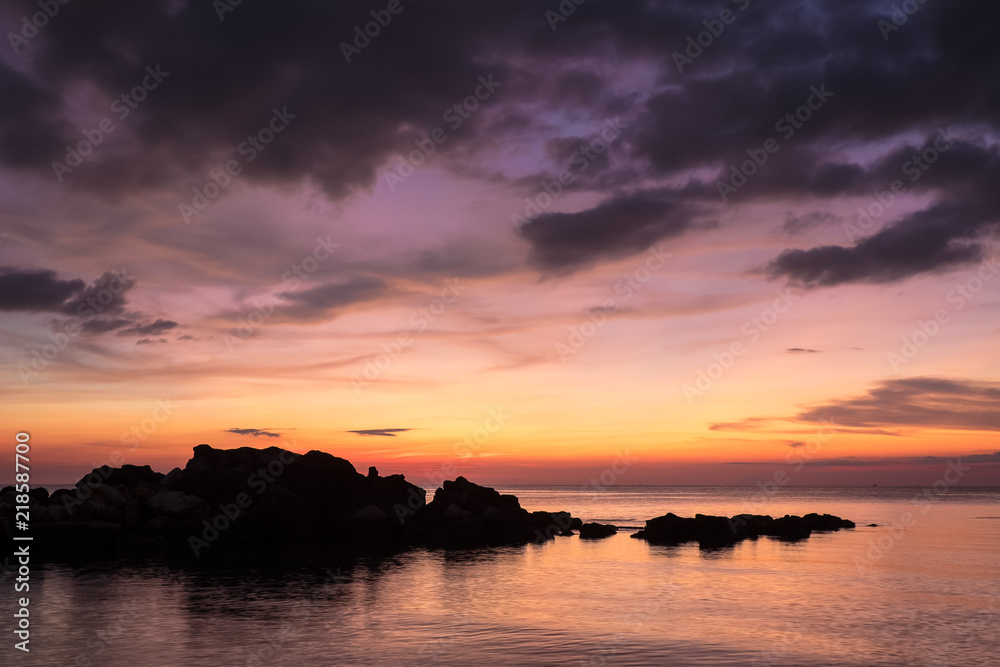 Sea and silhouette of rocks outlined against the sky in the dusk