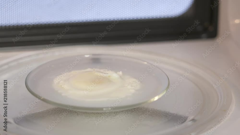 Poached egg rotating on a plate inside microwave Poached egg rotating on a plate inside microwave