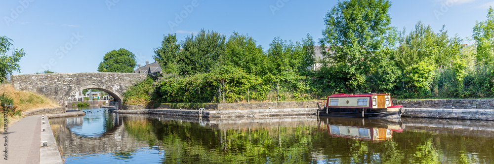 Bridge and barge reflecting in the water of Brecon Canal basin  in Brecon, Beacons National Park, Wales, UK