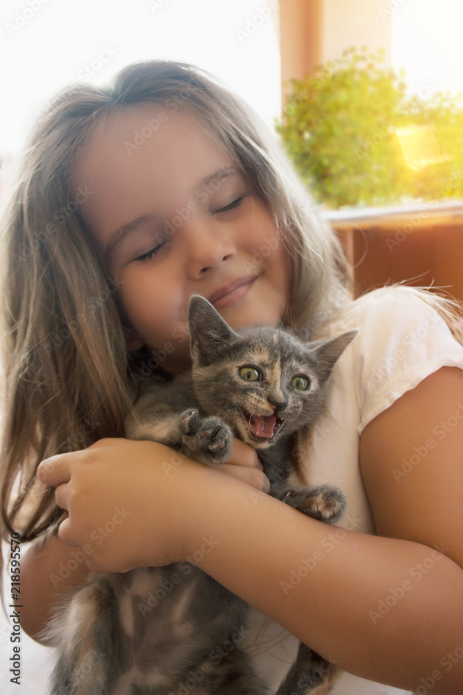 A little girl is very emotionally holding a kitten. A little girl is very emotionally holding a kitten.
