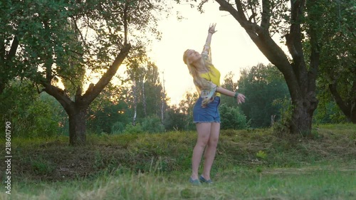 young blond hippie woman dancing on grass in park at sunset. Warm summer day and soft backlight. happy woman is dancing. the middle plan. a hot summer day. Slow motiom HD photo