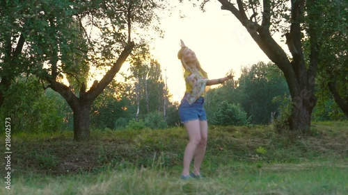 young blond hippie woman dancing on grass in park at sunset. Warm summer day and soft backlight. happy woman is dancing. the middle plan. a hot summer day. Slow motiom HD photo