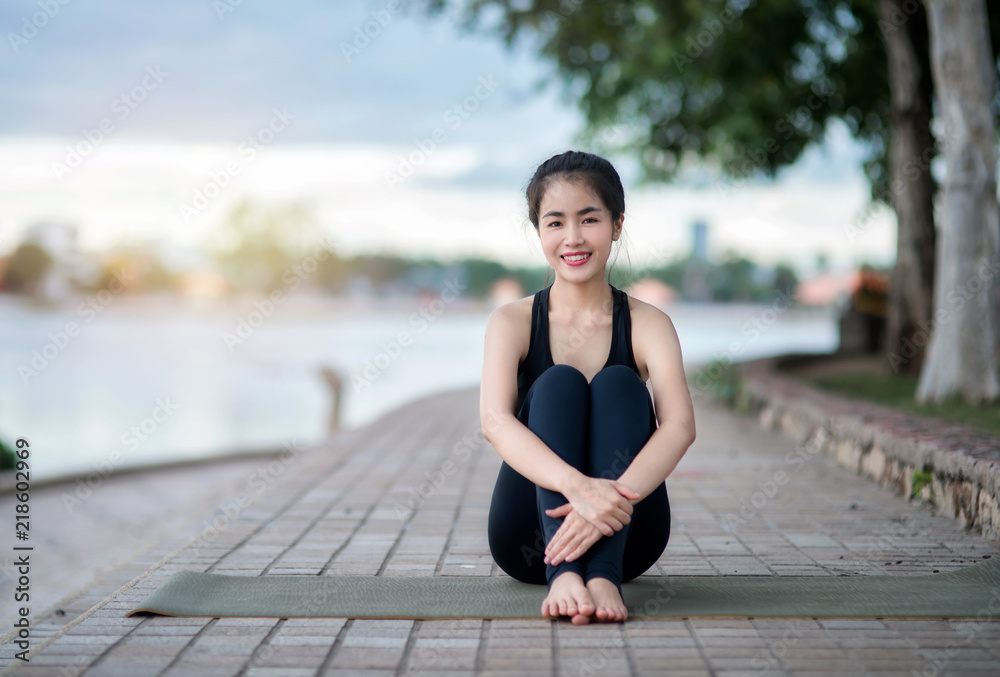 Portrait of a beautiful woman doing pilates exercise.Young attractive smiling lady practicing yoga sitting in Seated forward bend exercise, close up Fitness asian female, selective focus.