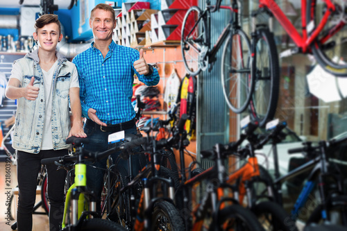 Man and boy holding thumbs up while buying new bicycle