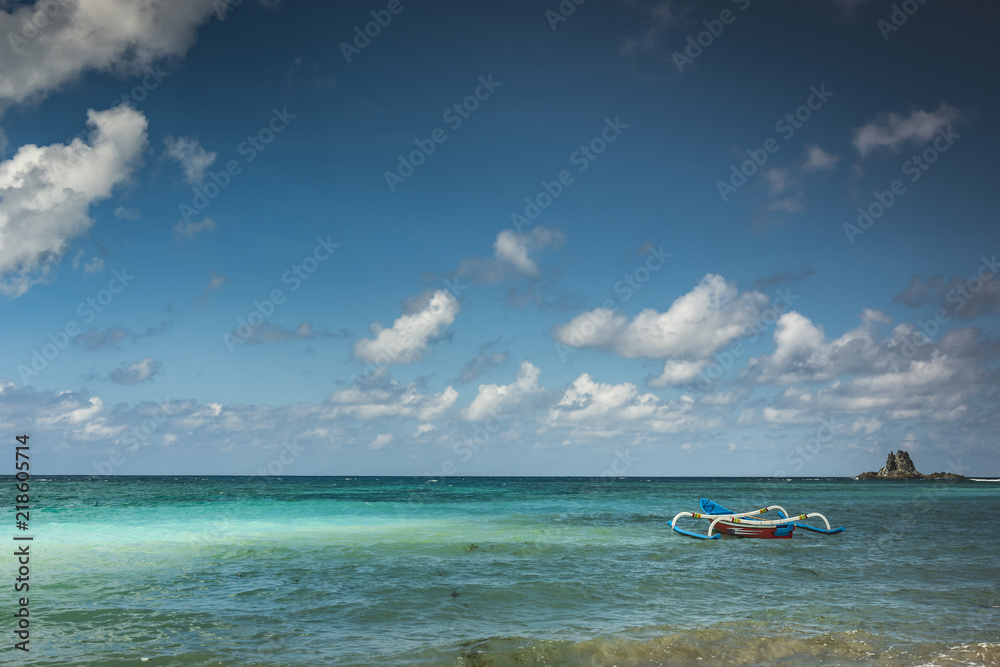 Beautiful beach view in Lombok Island with cloudy blue sky and traditional fishing boat