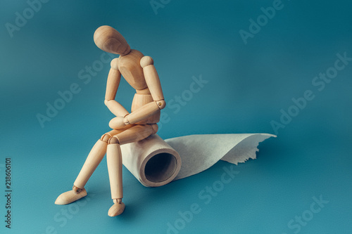 Obraz na płótnie Wooden figure sit on a roll of toilet paper. Concept of the problem with digestion. w salonie