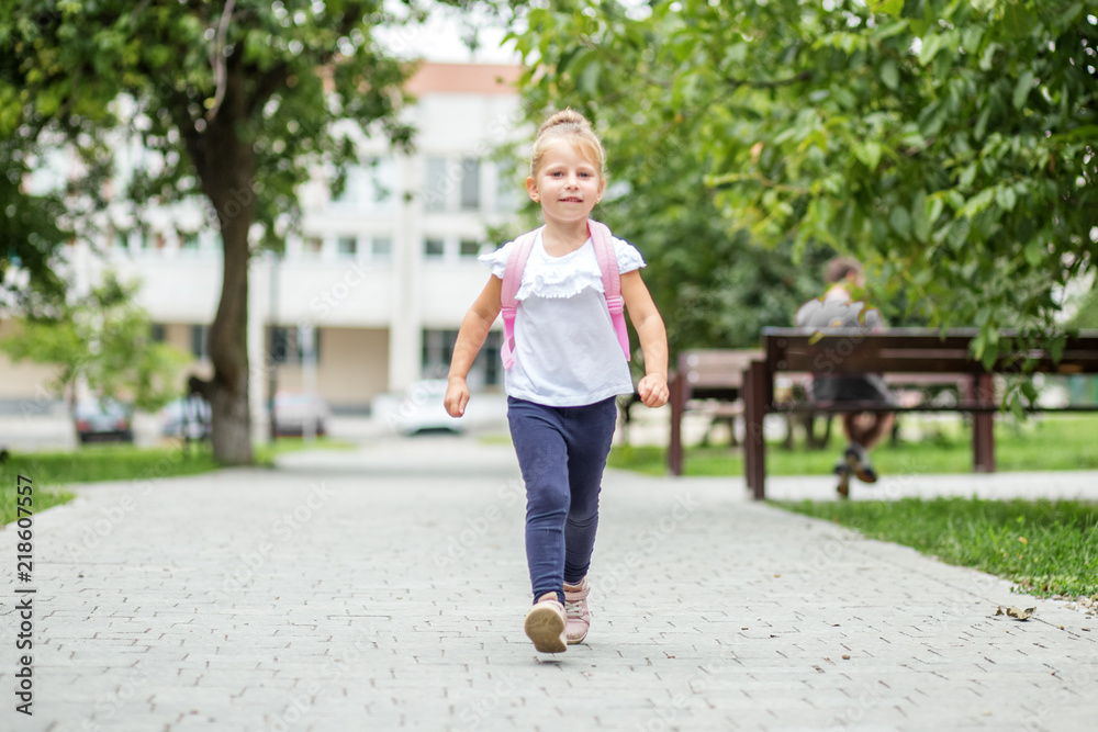 A little girl comes with a backpack for lessons. The concept of school, study, education, friendship, childhood