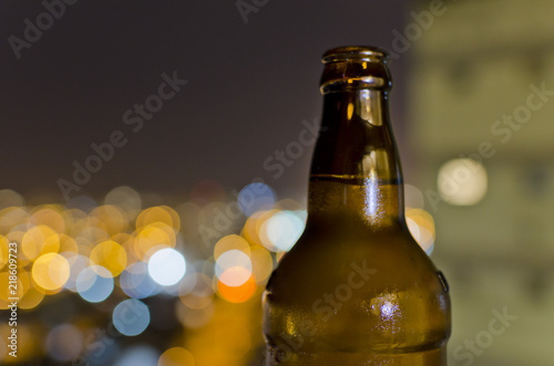 botella de cerveza con fondo de luces de ciudad © Martin