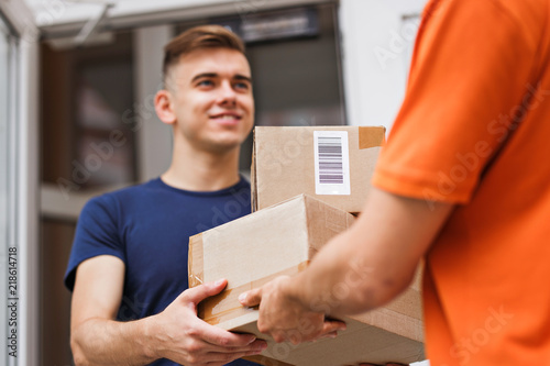 A person wearing an orange T-shirt is delivering parcels to a satisfied client. Friendly worker, high quality delivery service.