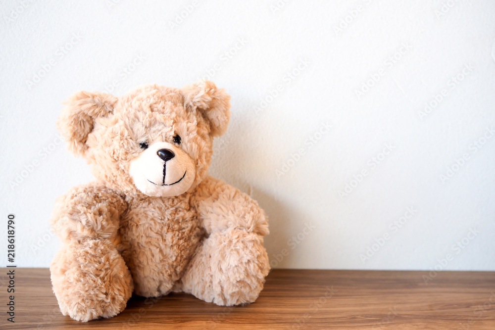 Cute Teddy Bear sitting alone with white wall on wooden table Cute Teddy Bear sitting alone with white wall on wooden table