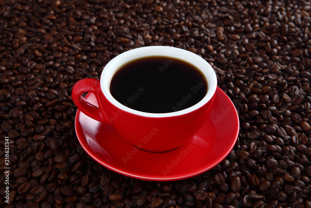 Coffee splash in red cup with coffee beans in background Coffee splash in red cup with coffee beans in background