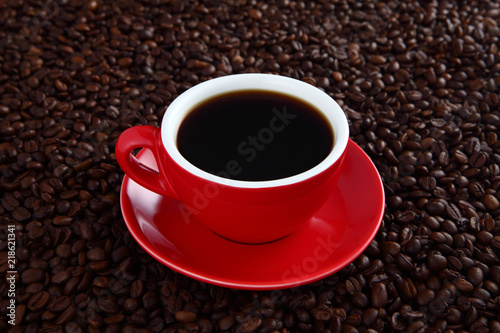 Coffee splash in red cup with coffee beans in background