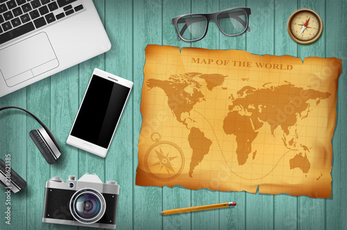 Green wooden table with technology devices and retro map. Travel background.