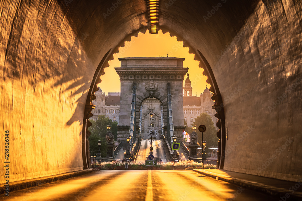 Fototapeta premium Budapeszt, Węgry - wejście do tunelu Zamku Królewskiego o wschodzie słońca z mostem łańcuchowym Szechenyi i budynkiem Akademii Nauk w tle