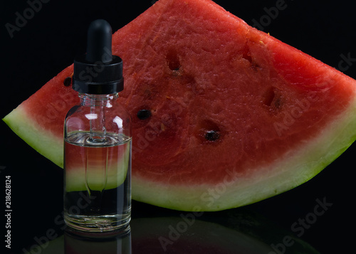 liquid for electronic cigarette, on a black background and ripe watermelon