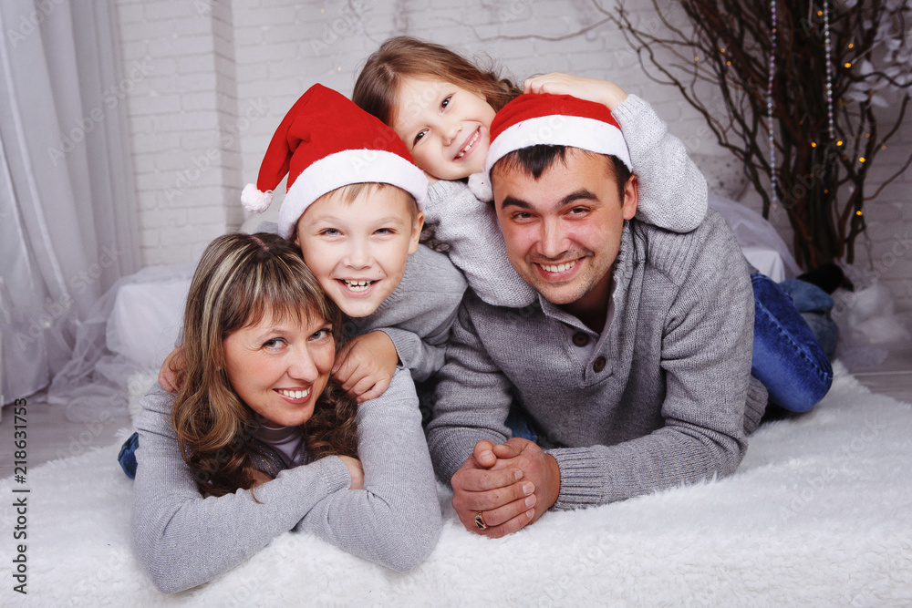 Portrait of four happy family members in Santa caps looking at camera with smiles Portrait of four happy family members in Santa caps looking at camera with smiles
