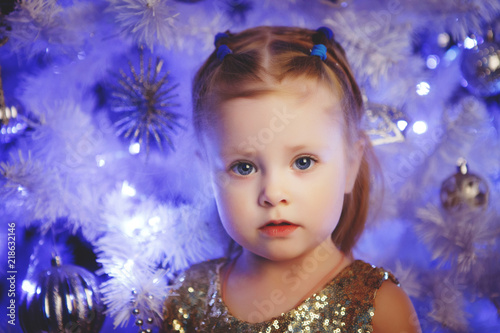 Blonde child with a Christmas tree. Luxurious Christmas decoration.