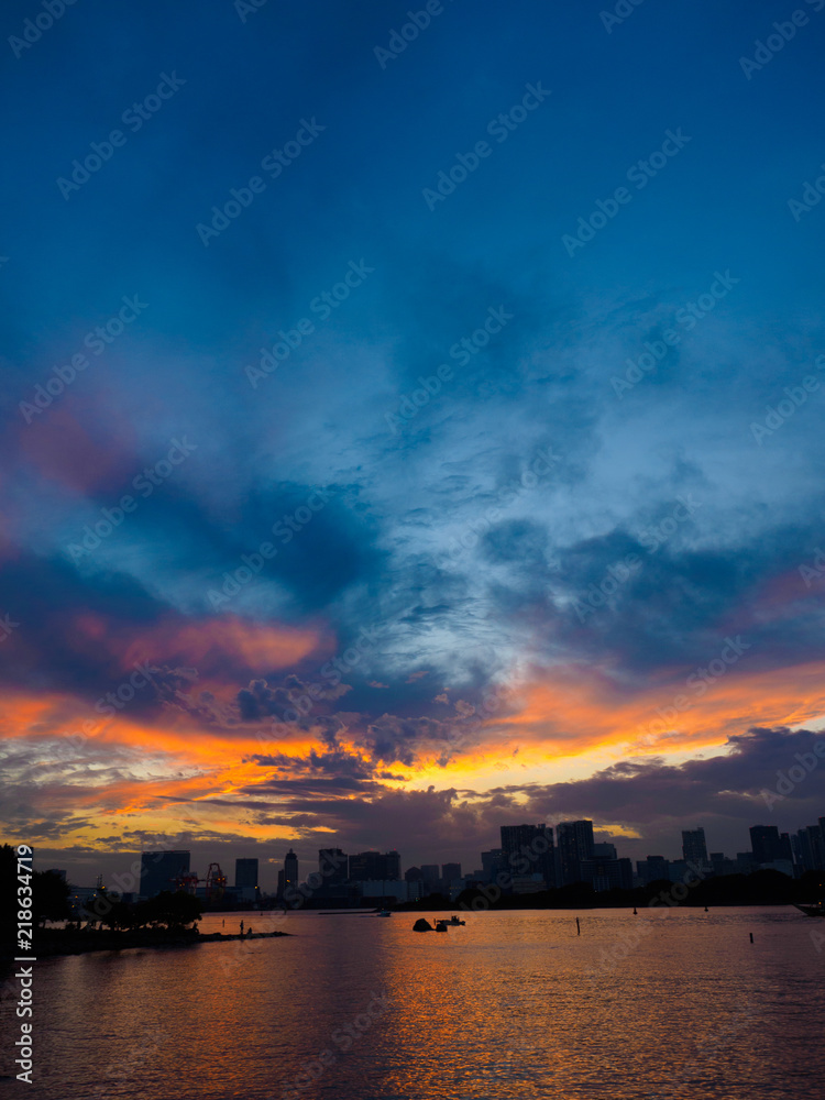 It is a beautiful sunset seen from the seaside. This place is Odaiba Beach Park in Tokyo, Japan. Clouds are dyed red beautifully. It is a very brilliant piece.