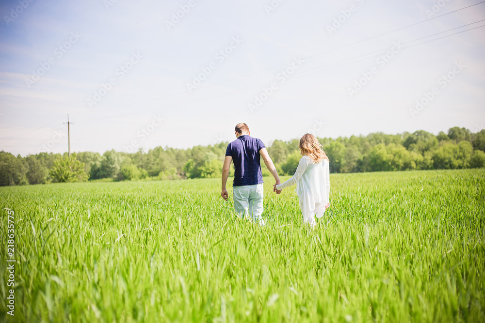 A young couple walking hand in hand through the field A young couple walking hand in hand through the field