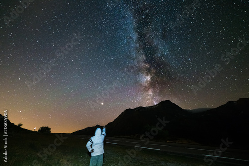 Fototapeta Naklejka Na Ścianę i Meble -  Stargazing one person looking at starry sky and milky way at high altitude on the Alps. Mars Planet on the left. Adventure and exploration in summer.