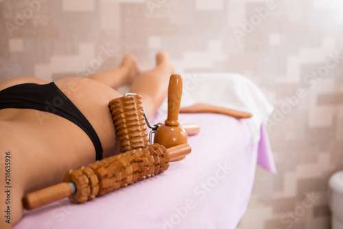 Hot girl on the massage table next to her is wooden massage tools for Maderotherapy. photo