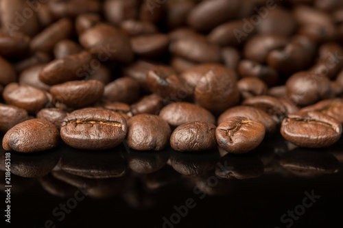 Close up pile of Coffee beans with reflection on glossy black materail