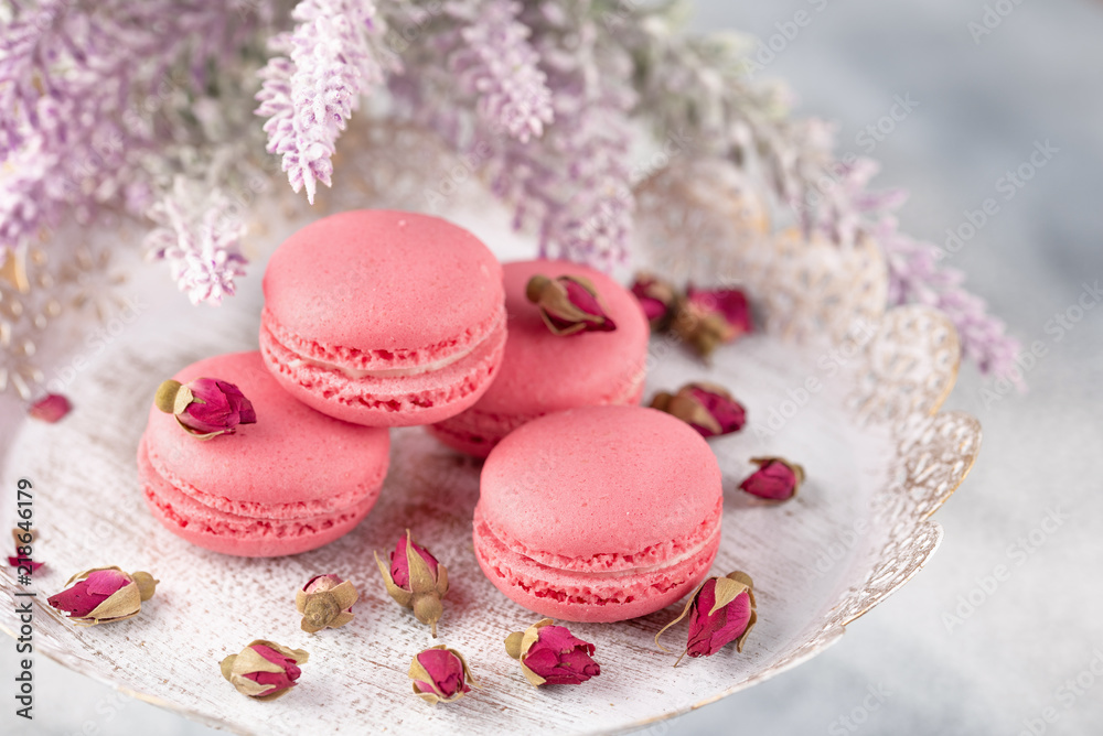 Pink macaroons on a vintage plate and dried flower buds. Pastel colored.