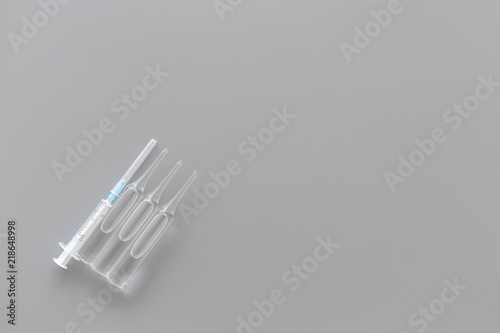 Flu vaccination concept. Syringe and ampoulie on grey background top view space for text