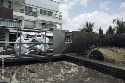 Two scientists checking water quality in wastewater treatment system.