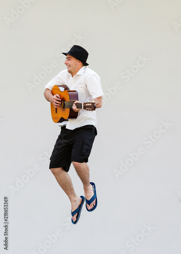 Man in sun hat jumping with guitar