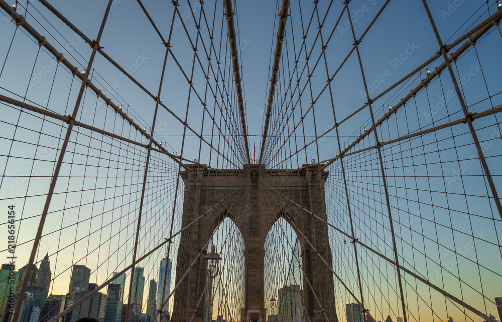 Fototapeta premium Brooklyn bridge w nowym jorku z geometryczną perspektywą o zachodzie słońca